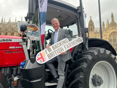 Stuart Andrew MP on a tractor holding "I'm backing British Farming" 